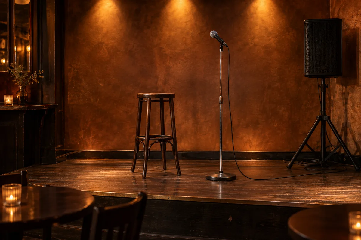 Scène de bar vide avec un tabouret haut, un pied de micro et une enceinte noire sur trépied